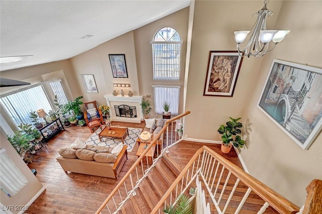 living room featuring high vaulted ceiling, a chandelier, and hardwood / wood-style floors