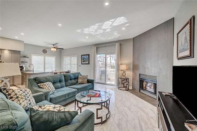 living room featuring ceiling fan, a healthy amount of sunlight, sink, and a fireplace