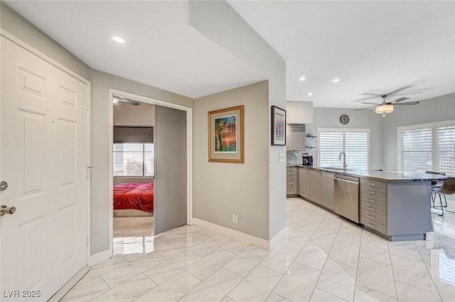 kitchen featuring sink, gray cabinetry, stainless steel dishwasher, ceiling fan, and kitchen peninsula