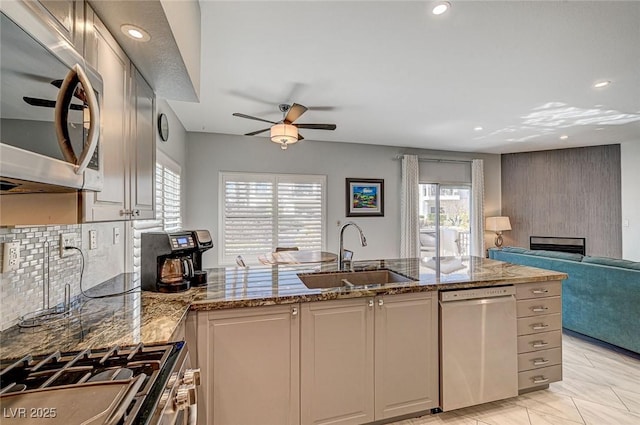 kitchen with sink, light stone countertops, a healthy amount of sunlight, and appliances with stainless steel finishes