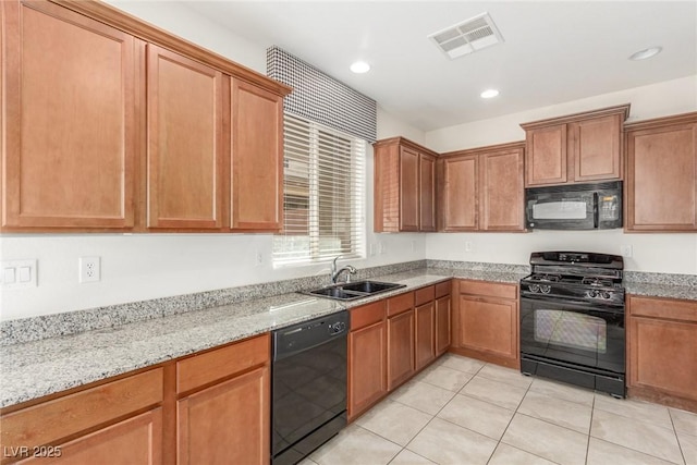 kitchen featuring light stone counters, sink, light tile patterned floors, and black appliances