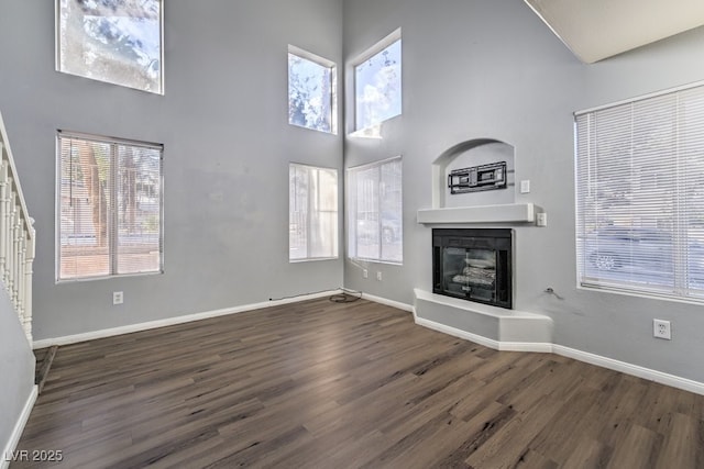 unfurnished living room with dark hardwood / wood-style flooring, a high ceiling, and a wealth of natural light