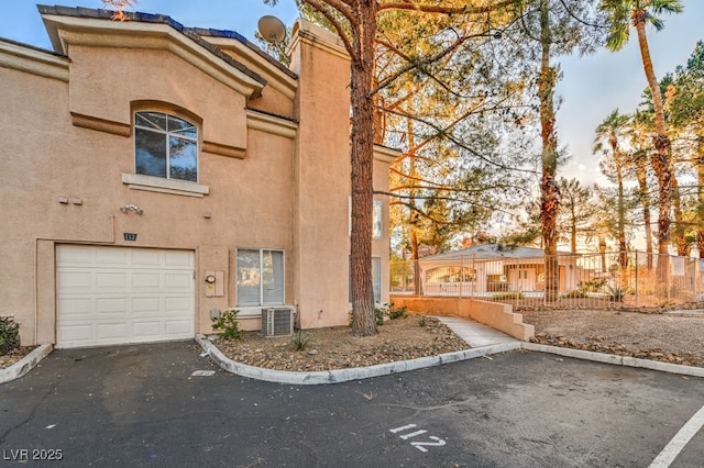 view of front facade featuring a garage, fence, and stucco siding