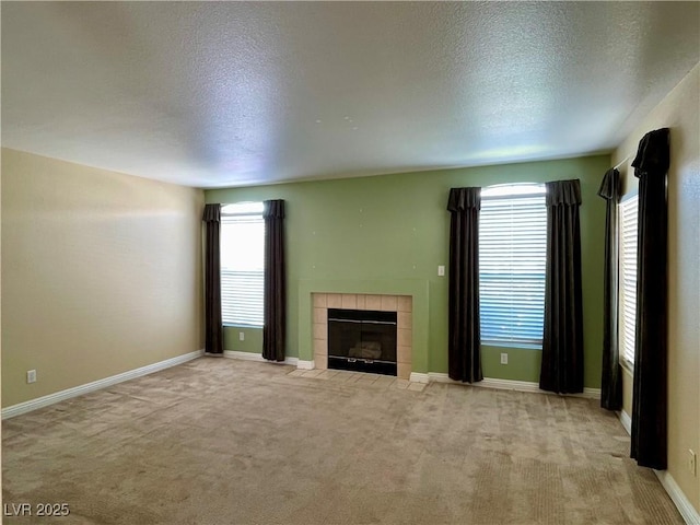 unfurnished living room with light carpet, a tile fireplace, and a textured ceiling