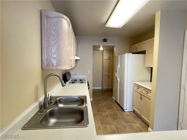 kitchen featuring white appliances, tile patterned flooring, sink, and light brown cabinets