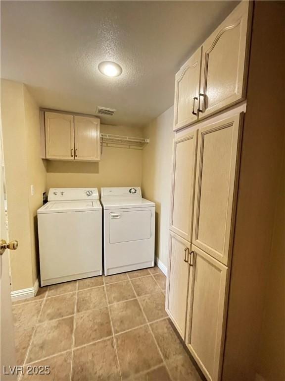 laundry area featuring cabinets, light tile patterned floors, a textured ceiling, and washing machine and clothes dryer