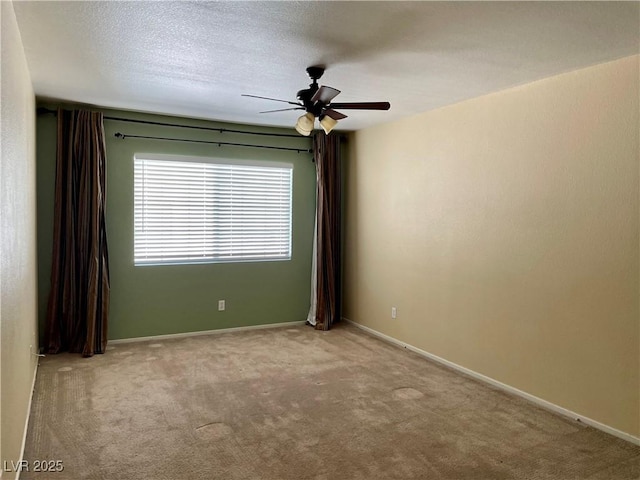 empty room featuring ceiling fan, light colored carpet, and a textured ceiling