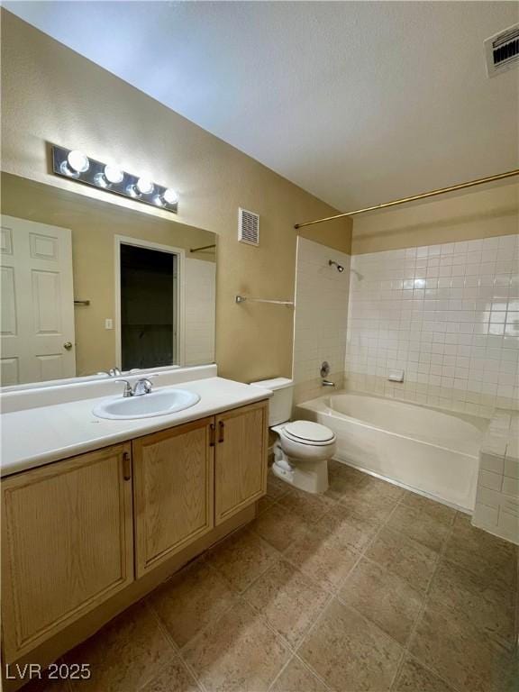 full bathroom with vanity, tiled shower / bath combo, and toilet