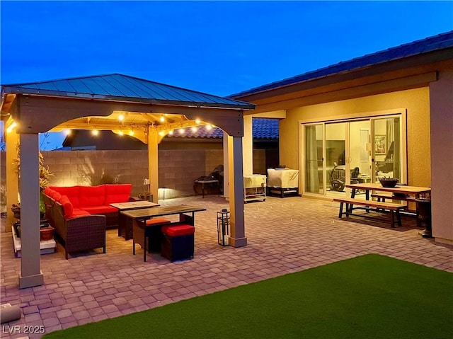 patio terrace at dusk featuring a gazebo and an outdoor living space with a fire pit