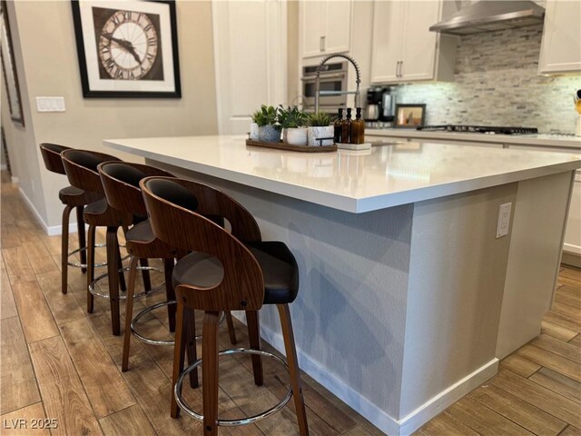 kitchen featuring gas cooktop, a breakfast bar, white cabinets, and light wood-type flooring