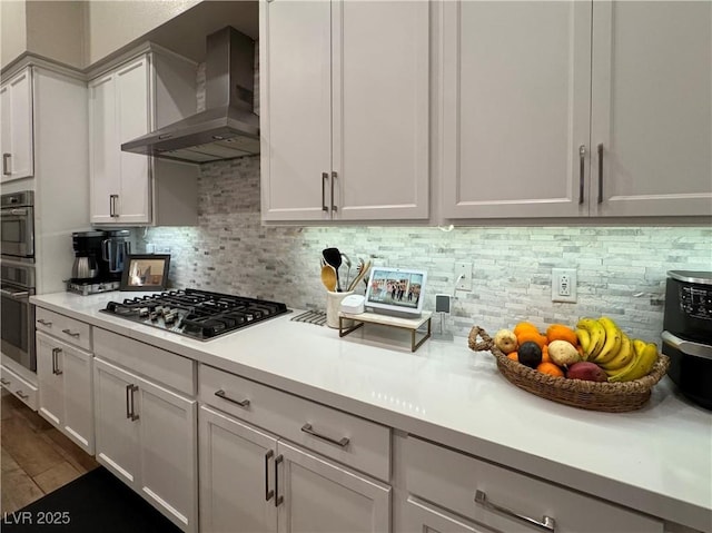 kitchen featuring stainless steel gas stovetop, tasteful backsplash, white cabinetry, dark hardwood / wood-style flooring, and wall chimney range hood