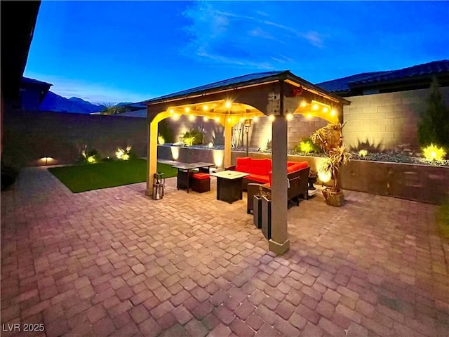 patio terrace at dusk featuring a mountain view, a gazebo, and an outdoor living space with a fire pit