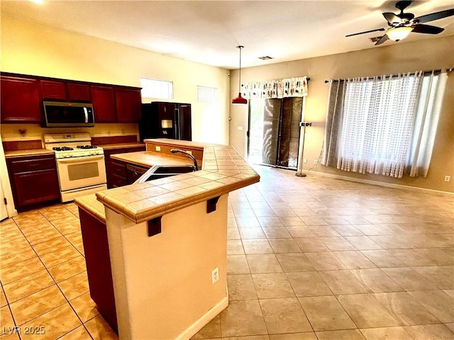 kitchen featuring pendant lighting, sink, white range with gas cooktop, tile counters, and black fridge with ice dispenser