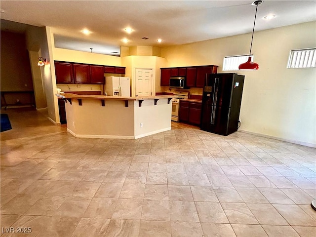 kitchen featuring pendant lighting, white appliances, a breakfast bar, and a center island with sink