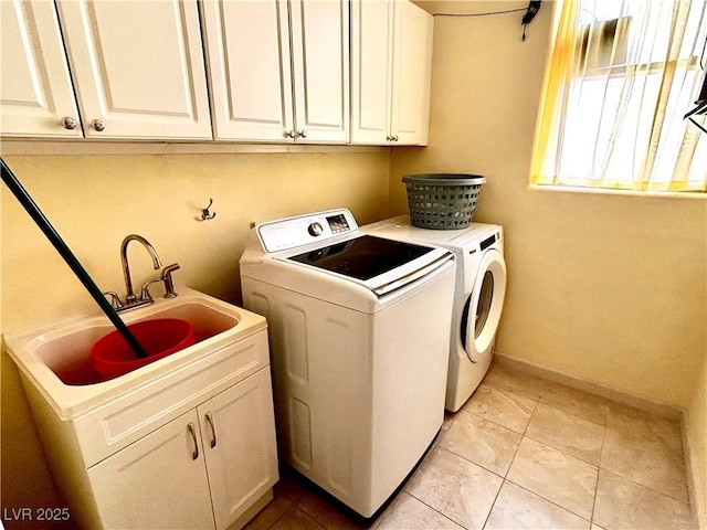 washroom featuring cabinets, sink, light tile patterned floors, and washing machine and clothes dryer