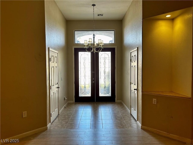 entryway featuring plenty of natural light, french doors, and a chandelier