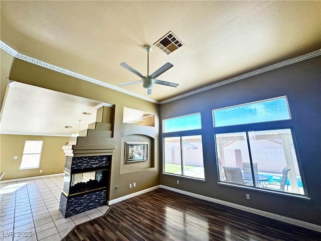 unfurnished living room with hardwood / wood-style flooring, ceiling fan, crown molding, and a textured ceiling