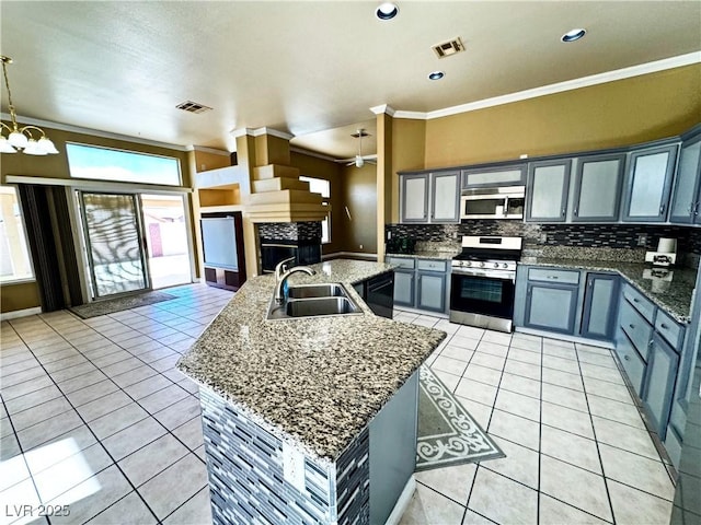 kitchen featuring sink, appliances with stainless steel finishes, an island with sink, light tile patterned flooring, and decorative light fixtures