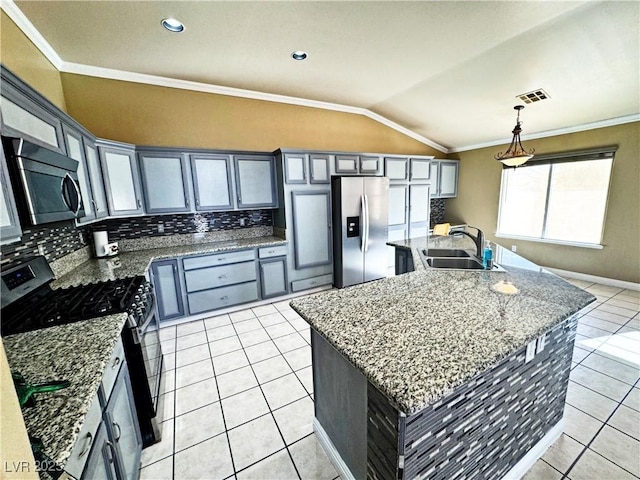 kitchen featuring sink, hanging light fixtures, appliances with stainless steel finishes, light stone countertops, and a kitchen island with sink