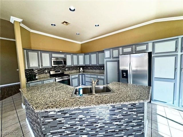 kitchen with stainless steel appliances, an island with sink, sink, and dark stone counters