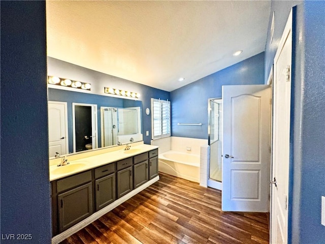 bathroom with hardwood / wood-style flooring, vaulted ceiling, shower with separate bathtub, and vanity