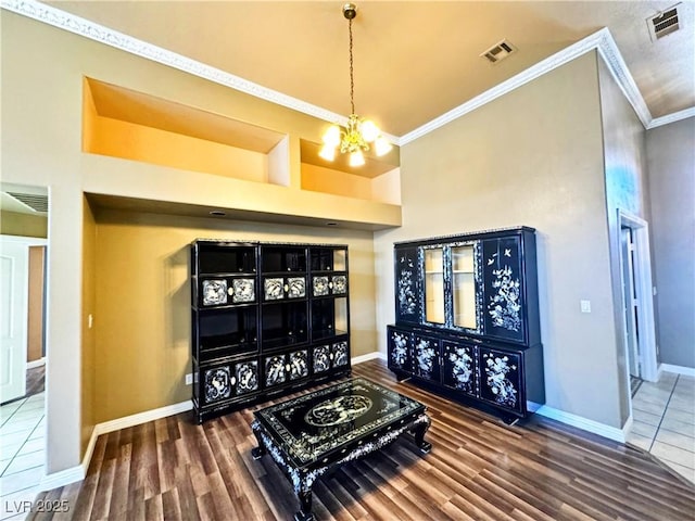 interior space with an inviting chandelier, a towering ceiling, ornamental molding, and dark hardwood / wood-style flooring