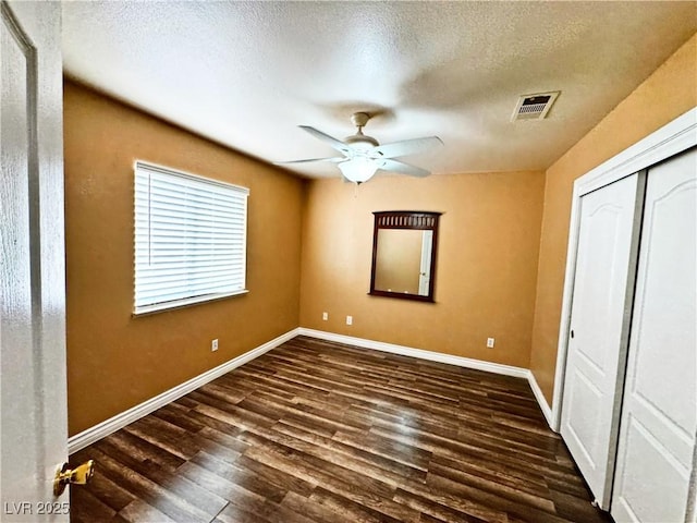 unfurnished bedroom with ceiling fan, a textured ceiling, dark hardwood / wood-style flooring, and a closet