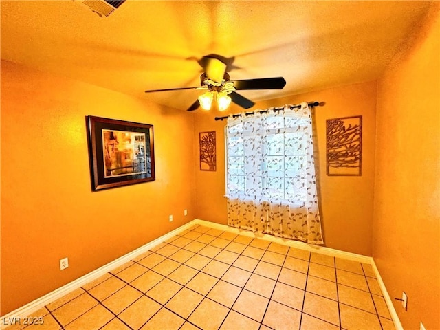 empty room with light tile patterned floors, a textured ceiling, and ceiling fan