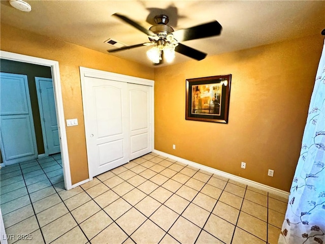 unfurnished bedroom with ceiling fan, a closet, and light tile patterned floors