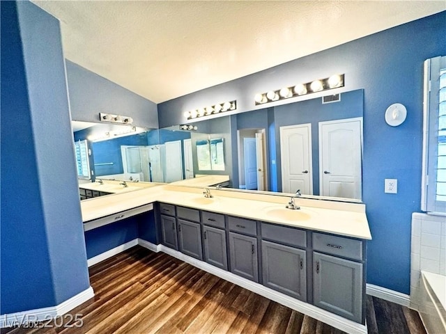 bathroom with vanity, lofted ceiling, hardwood / wood-style floors, and a tub to relax in