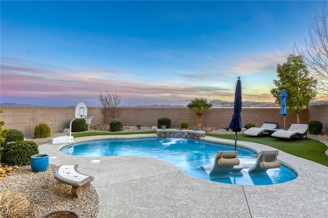 pool at dusk featuring pool water feature and a patio