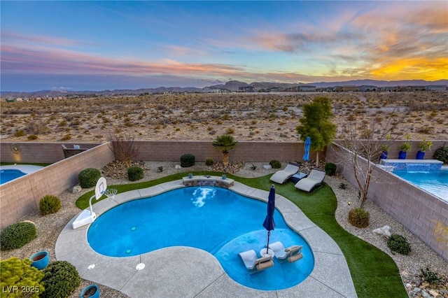 pool at dusk featuring a mountain view and pool water feature