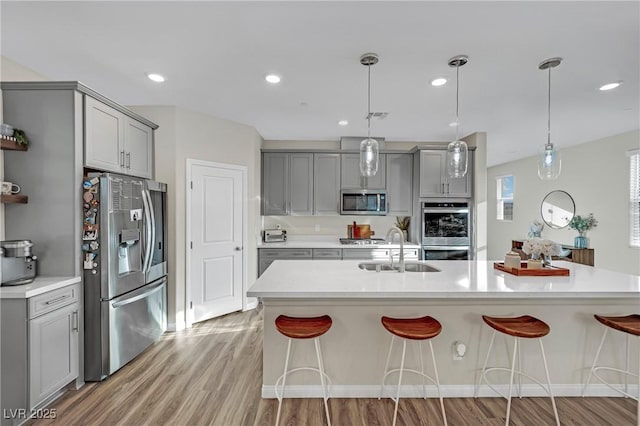 kitchen with stainless steel appliances, gray cabinetry, and decorative light fixtures