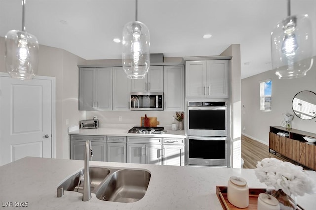 kitchen with stainless steel appliances, hardwood / wood-style flooring, sink, and gray cabinetry