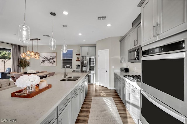 kitchen with sink, gray cabinets, stainless steel appliances, light stone countertops, and decorative light fixtures