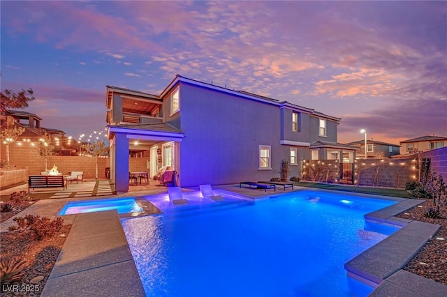 pool at dusk featuring a patio area and a fire pit