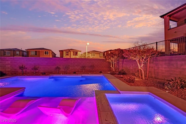 pool at dusk with an in ground hot tub