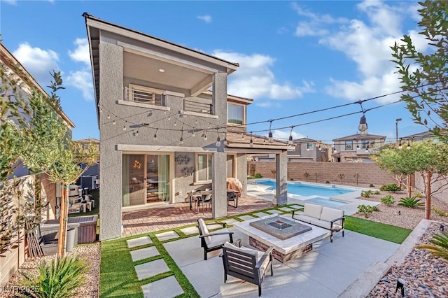 back of house featuring a swimming pool with hot tub, an outdoor fire pit, and a patio