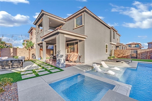 back of property featuring a fenced in pool and a patio