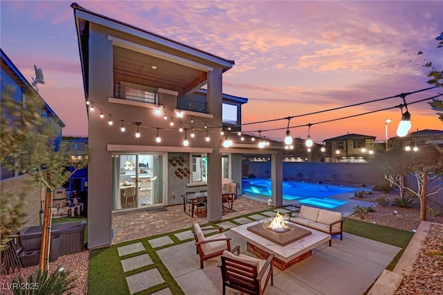 patio terrace at dusk featuring a pool with hot tub and an outdoor fire pit