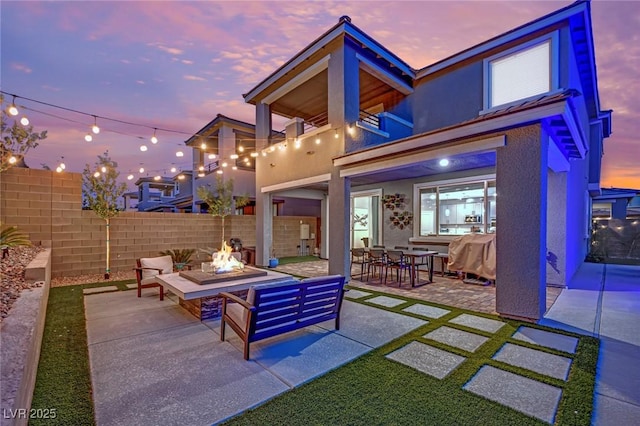 patio terrace at dusk featuring a balcony and an outdoor fire pit