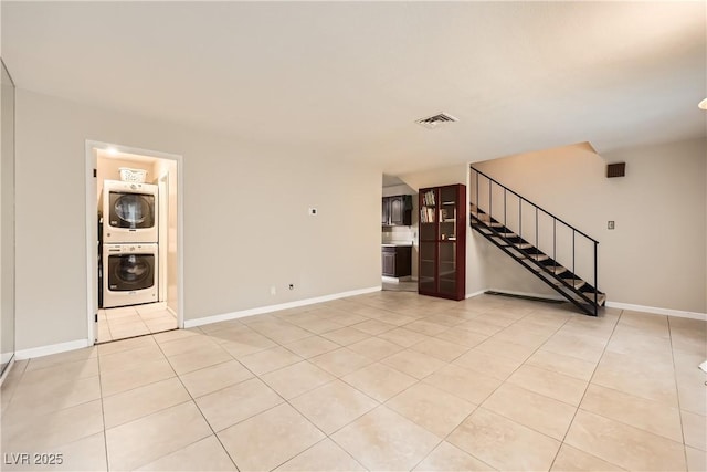 unfurnished living room with stacked washing maching and dryer and light tile patterned flooring