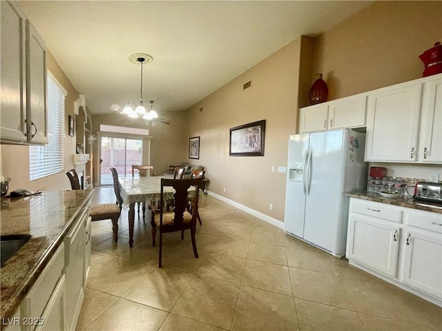 dining area featuring an inviting chandelier, light tile patterned floors, and vaulted ceiling