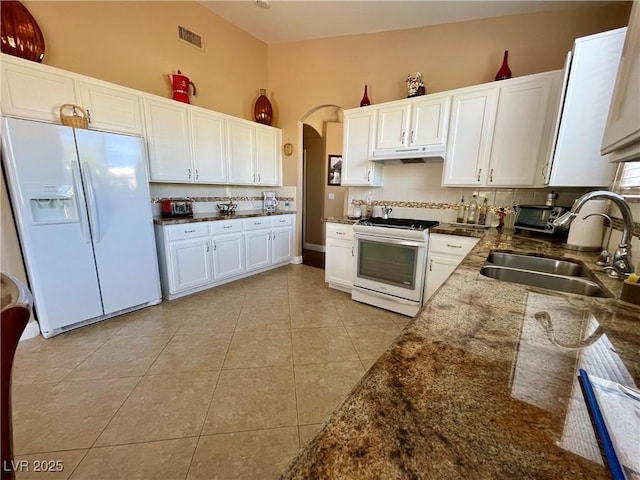 kitchen featuring white cabinetry, sink, backsplash, light tile patterned floors, and white appliances