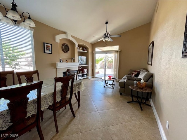 dining space with vaulted ceiling, built in features, a fireplace, light tile patterned floors, and ceiling fan