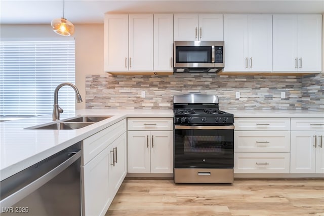 kitchen with decorative light fixtures, white cabinetry, sink, backsplash, and stainless steel appliances