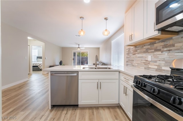 kitchen with pendant lighting, sink, white cabinets, and appliances with stainless steel finishes