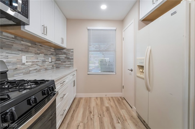 kitchen with white cabinetry, decorative backsplash, white refrigerator with ice dispenser, and black gas stove