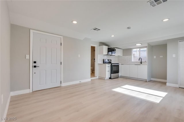 kitchen featuring sink, white cabinets, backsplash, stainless steel appliances, and light hardwood / wood-style flooring