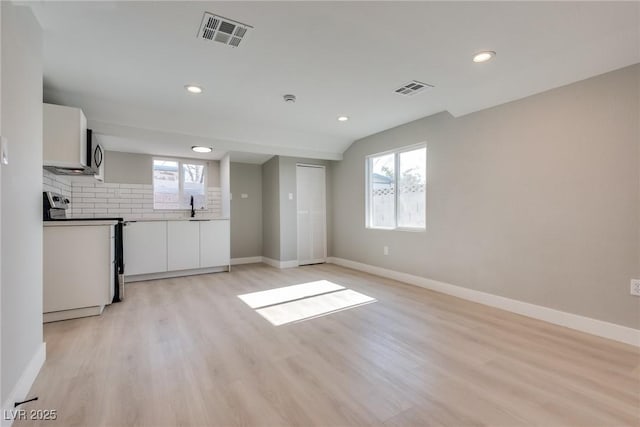 unfurnished living room with sink and light hardwood / wood-style floors